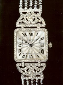 Orologio da polso squadrato in oro e platino il cui quadrante è tempestato di brillanti. Il bracciale è composto da perle e onice. Cartier, Parigi, 1912.